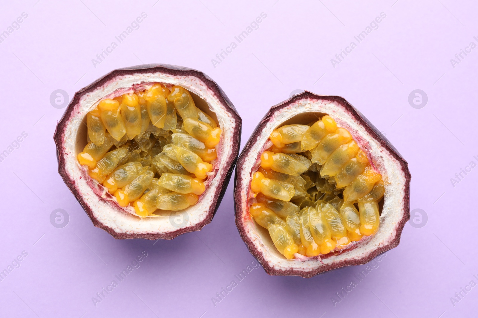 Halves of fresh passion fruit on violet background, closeup Photo of Halves of fresh passion fruit on violet background, closeup