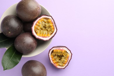 Photo of Fresh passion fruits with green leaves on violet background, flat lay. Space for text