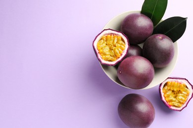 Photo of Fresh passion fruits with green leaves on violet background, flat lay. Space for text