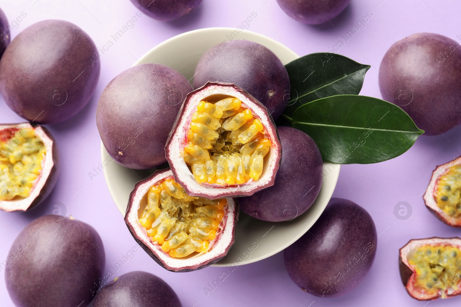 Fresh passion fruits with green leaves on violet background, above view Photo of Fresh passion fruits with green leaves on violet background, above view
