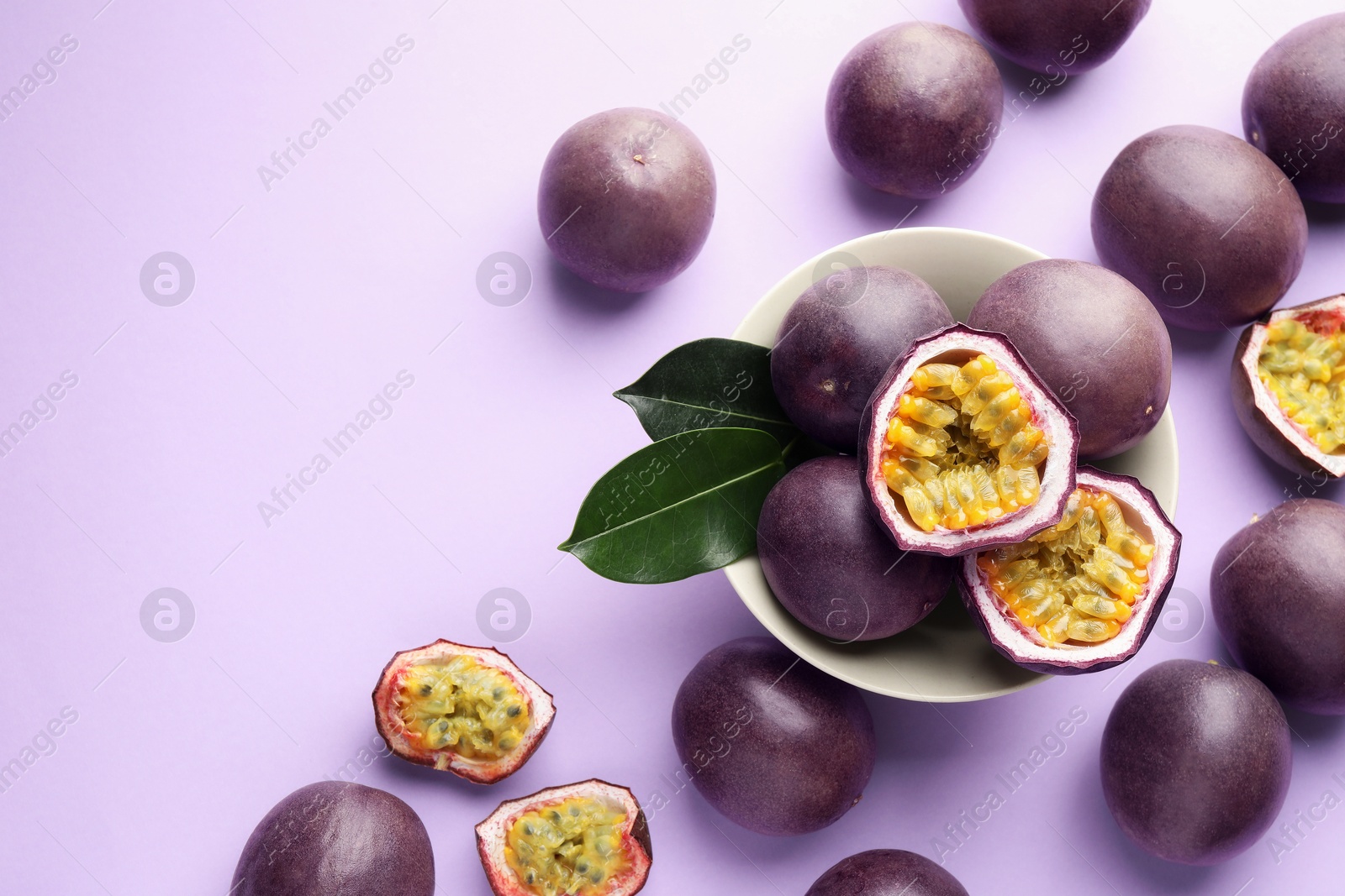 Fresh passion fruits with green leaves on violet background, flat lay. Space for text Photo of Fresh passion fruits with green leaves on violet background, flat lay. Space for text