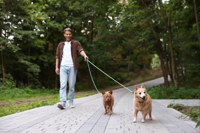Photo of Young man walking his cute dogs outdoors, selective focus