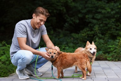 Photo of Young man petting his cute dogs while walking outdoors