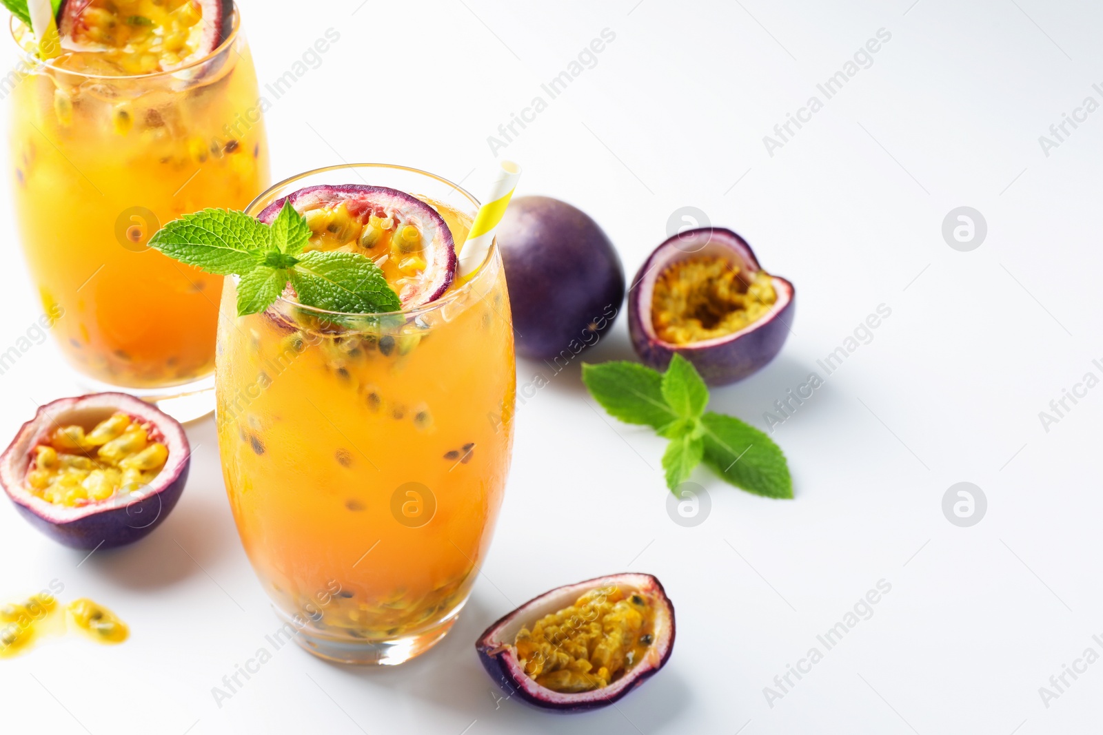 Photo of Tasty passion fruit drink with mint in glasses and fresh fruits on white table