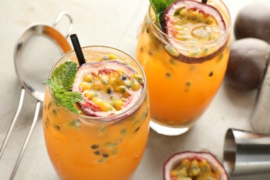 Photo of Tasty passion fruit drink with mint in glasses and fresh fruits on gray table, closeup