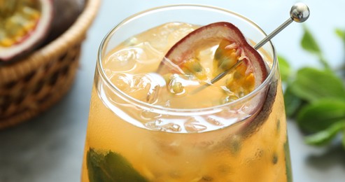 Photo of Tasty passion fruit drink in glass and fresh fruits on table, closeup