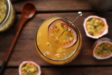 Photo of Tasty passion fruit drink in glass and fresh fruits on wooden table, flat lay