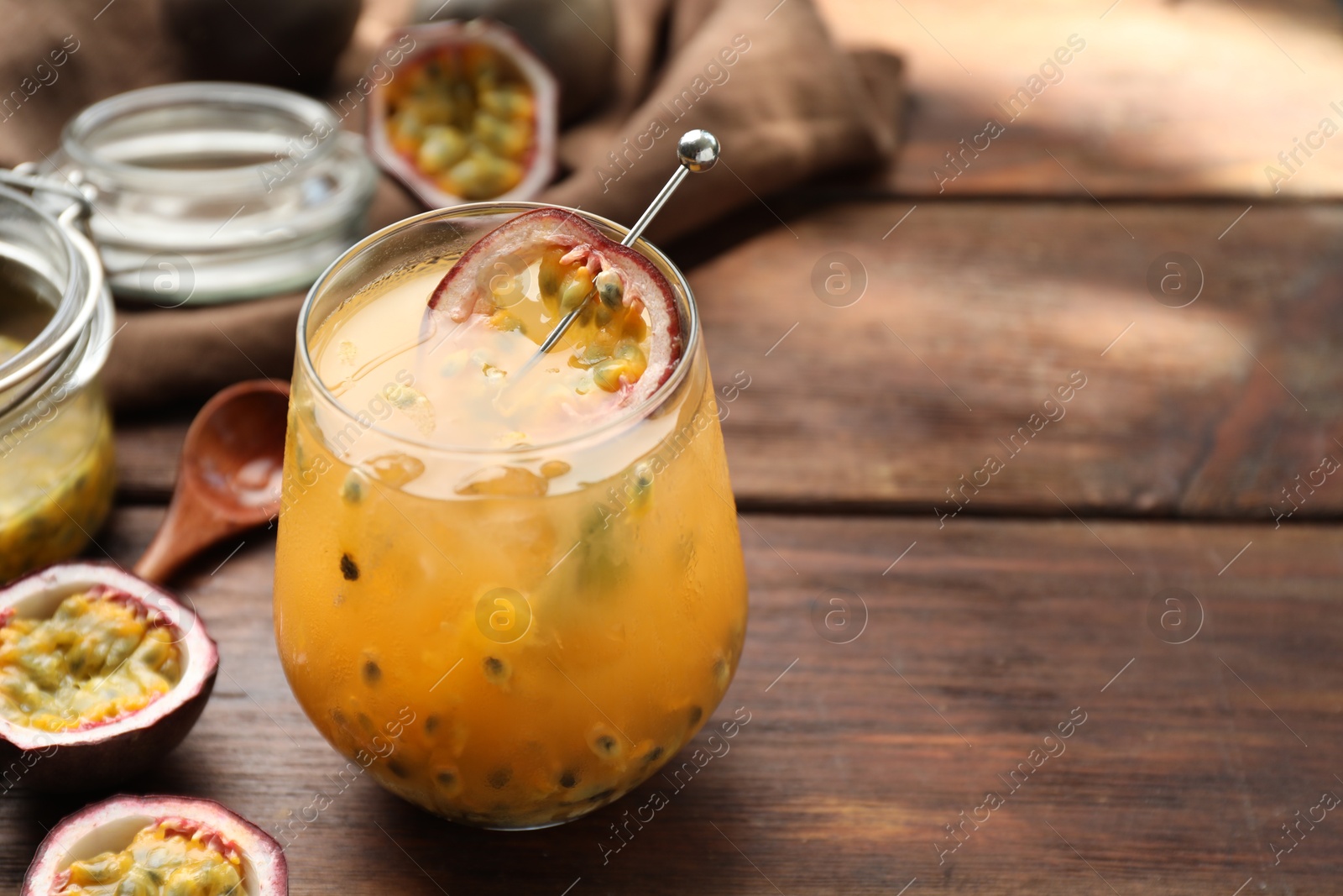 Photo of Tasty passion fruit drink in glass and fresh fruits on wooden table, closeup. Space for text