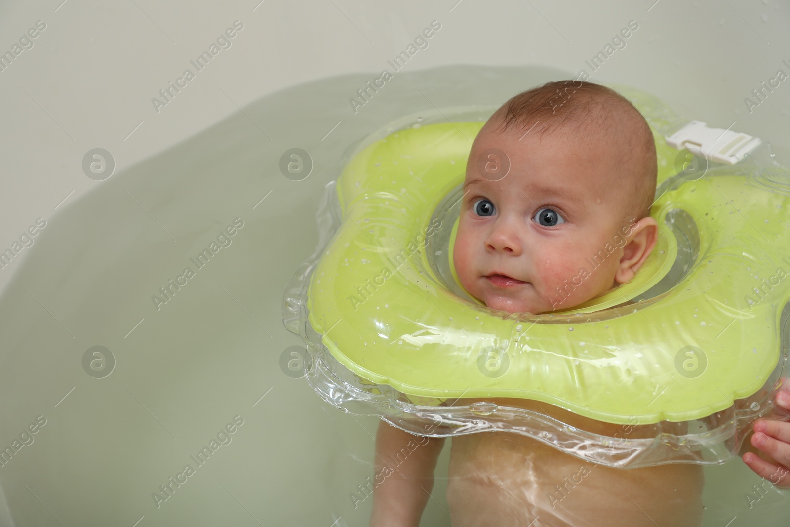 Photo of Cute little baby swimming with inflatable ring in bath