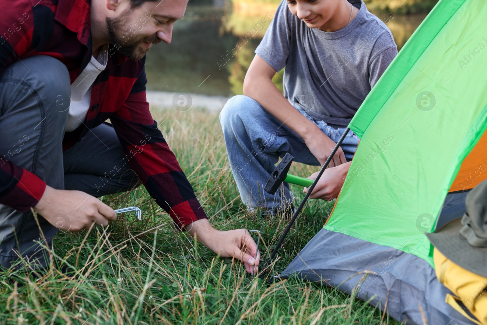 Father and son setting up camping tent outdoors, closeup Photo of Father and son setting up camping tent outdoors, closeup