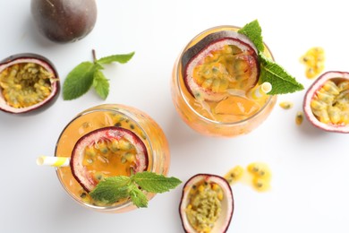 Photo of Tasty passion fruit drink with mint in glasses and fresh fruits on white table, flat lay