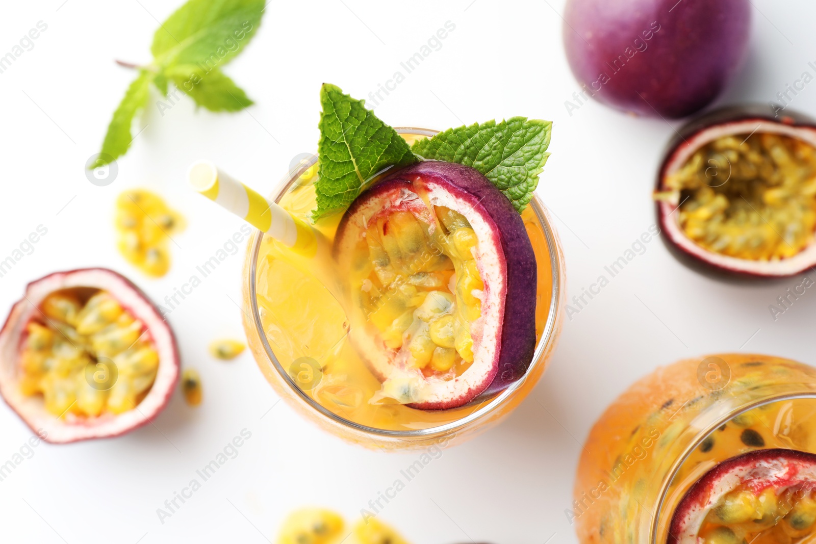 Photo of Tasty passion fruit drink with mint in glasses and fresh fruits on white table, flat lay