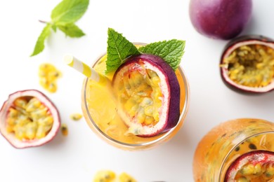 Photo of Tasty passion fruit drink with mint in glasses and fresh fruits on white table, flat lay