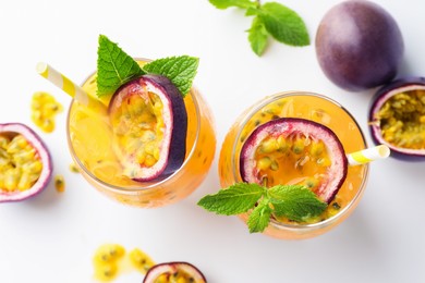 Photo of Tasty passion fruit drink with mint in glasses and fresh fruits on white table, flat lay