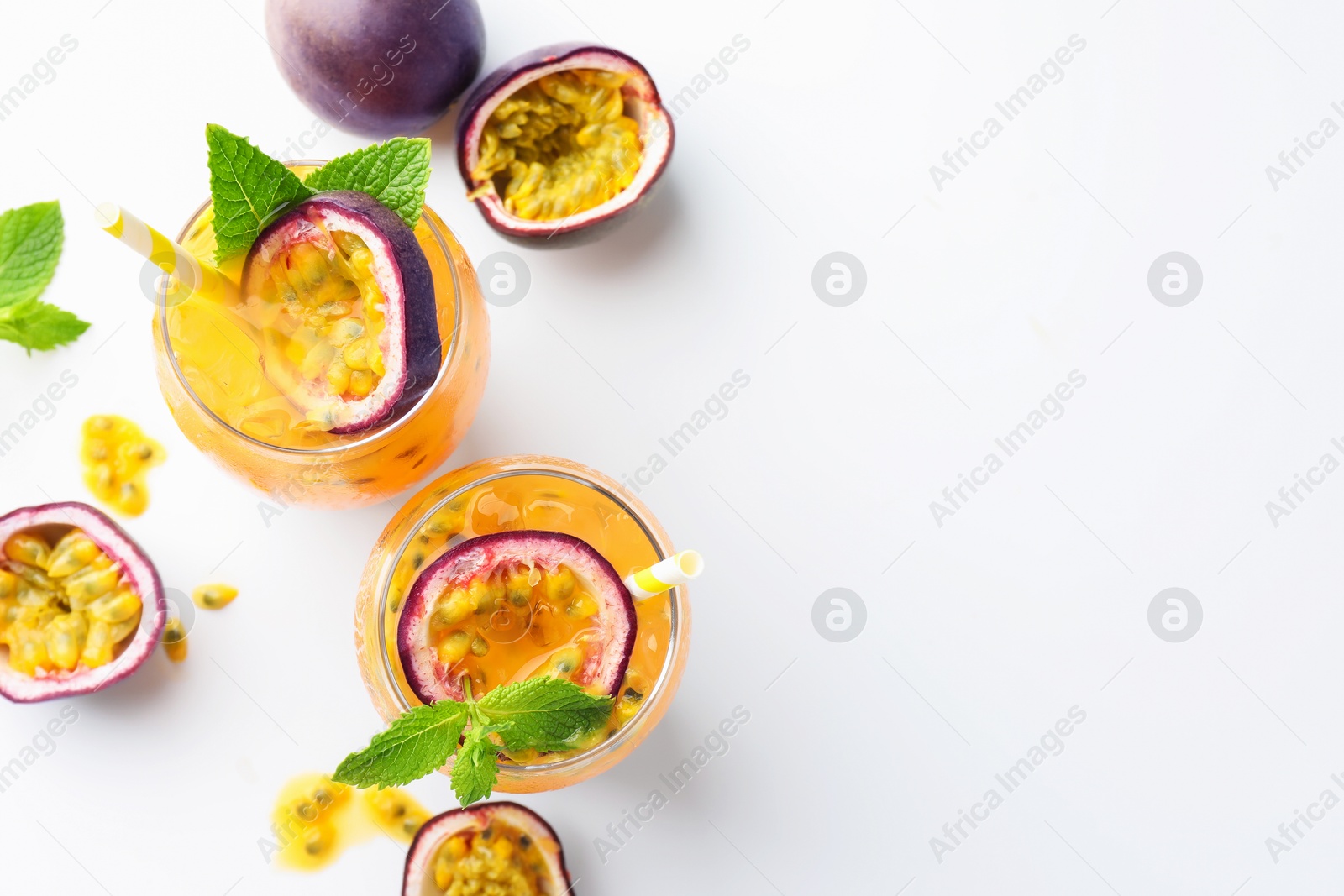 Photo of Tasty passion fruit drink with mint in glasses and fresh fruits on white table, flat lay. Space for text