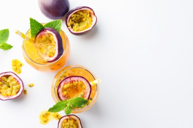 Photo of Tasty passion fruit drink with mint in glasses and fresh fruits on white table, flat lay. Space for text