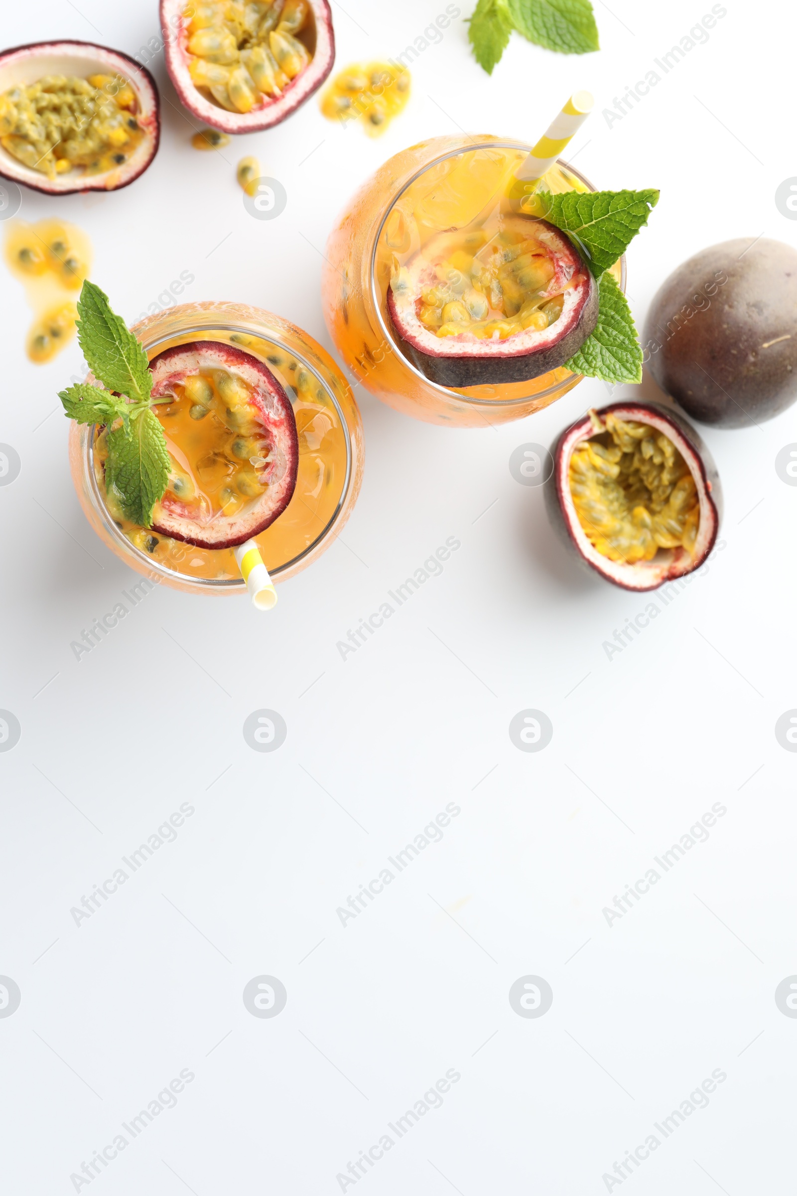 Photo of Tasty passion fruit drink with mint in glasses and fresh fruits on white table, flat lay. Space for text