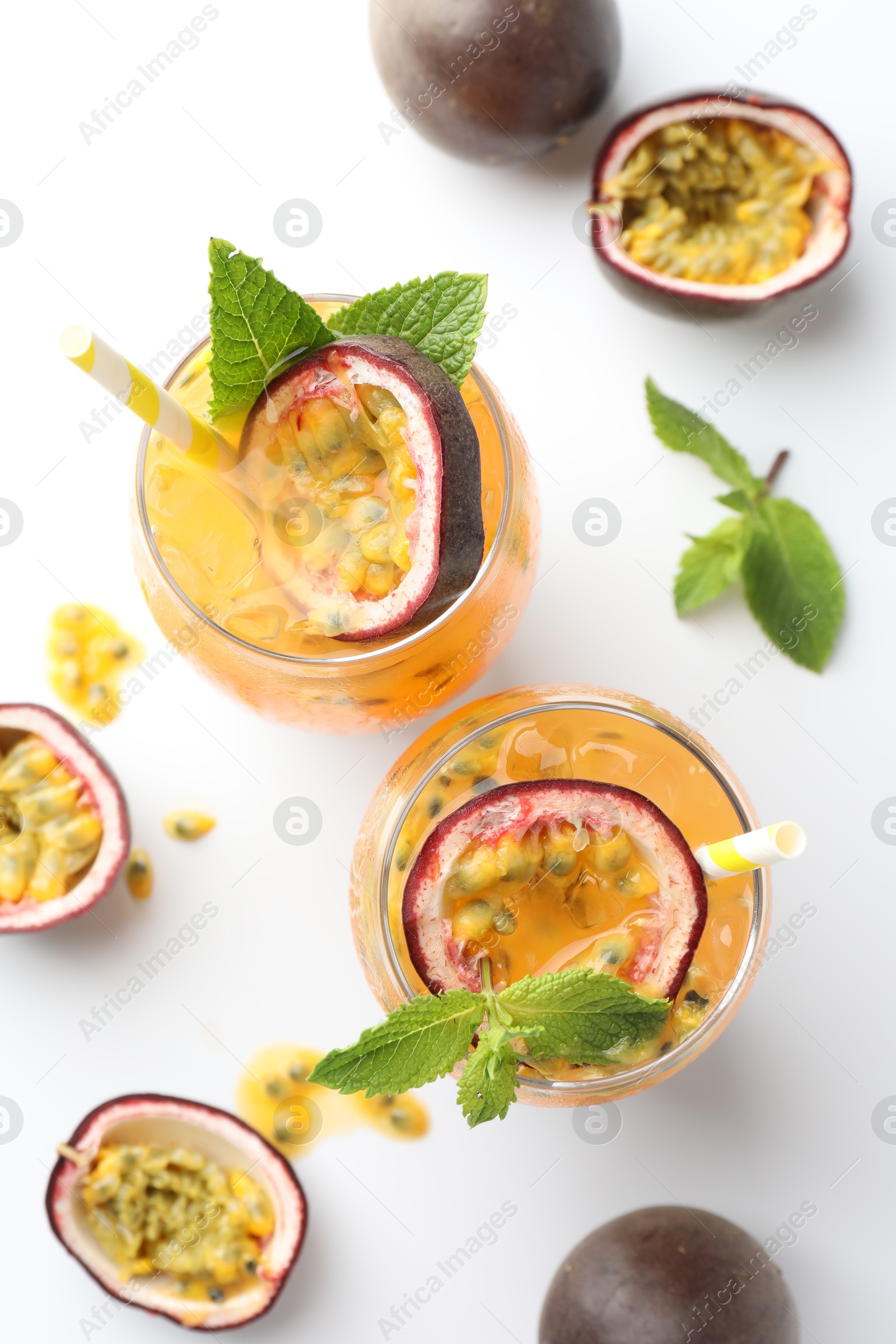 Photo of Tasty passion fruit drink with mint in glasses and fresh fruits on white table, flat lay