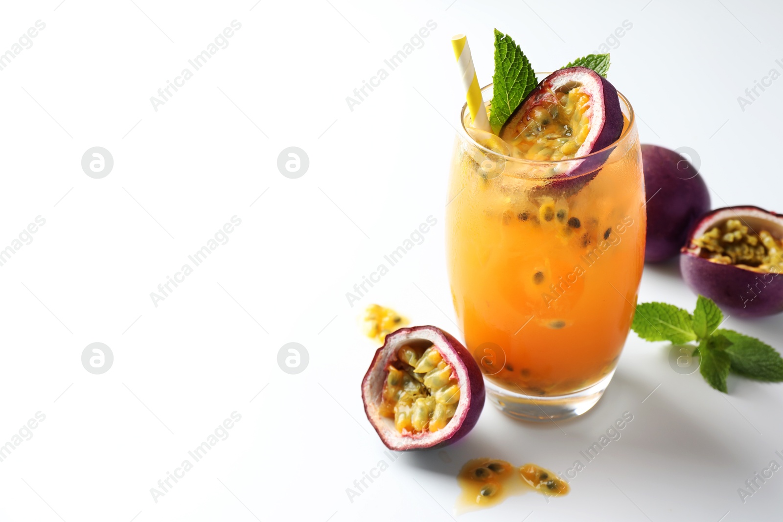 Tasty passion fruit drink with mint in glass and fresh fruits on white table, closeup. Space for text Photo of Tasty passion fruit drink with mint in glass and fresh fruits on white table, closeup. Space for text