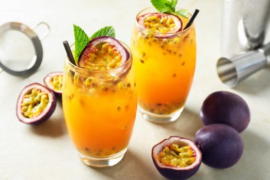 Photo of Tasty passion fruit drink with mint in glasses and fresh fruits on gray table, closeup