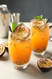 Photo of Tasty passion fruit drink with mint in glasses and fresh fruits on gray table, closeup