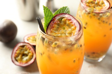 Photo of Tasty passion fruit drink with mint in glasses and fresh fruits on gray table, closeup