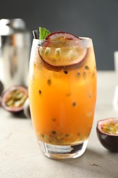 Photo of Tasty passion fruit drink in glass on gray table, closeup
