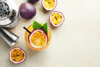 Photo of Tasty passion fruit drink with mint in glass, fresh fruits, shaker and jigger on gray table, flat lay. Space for text