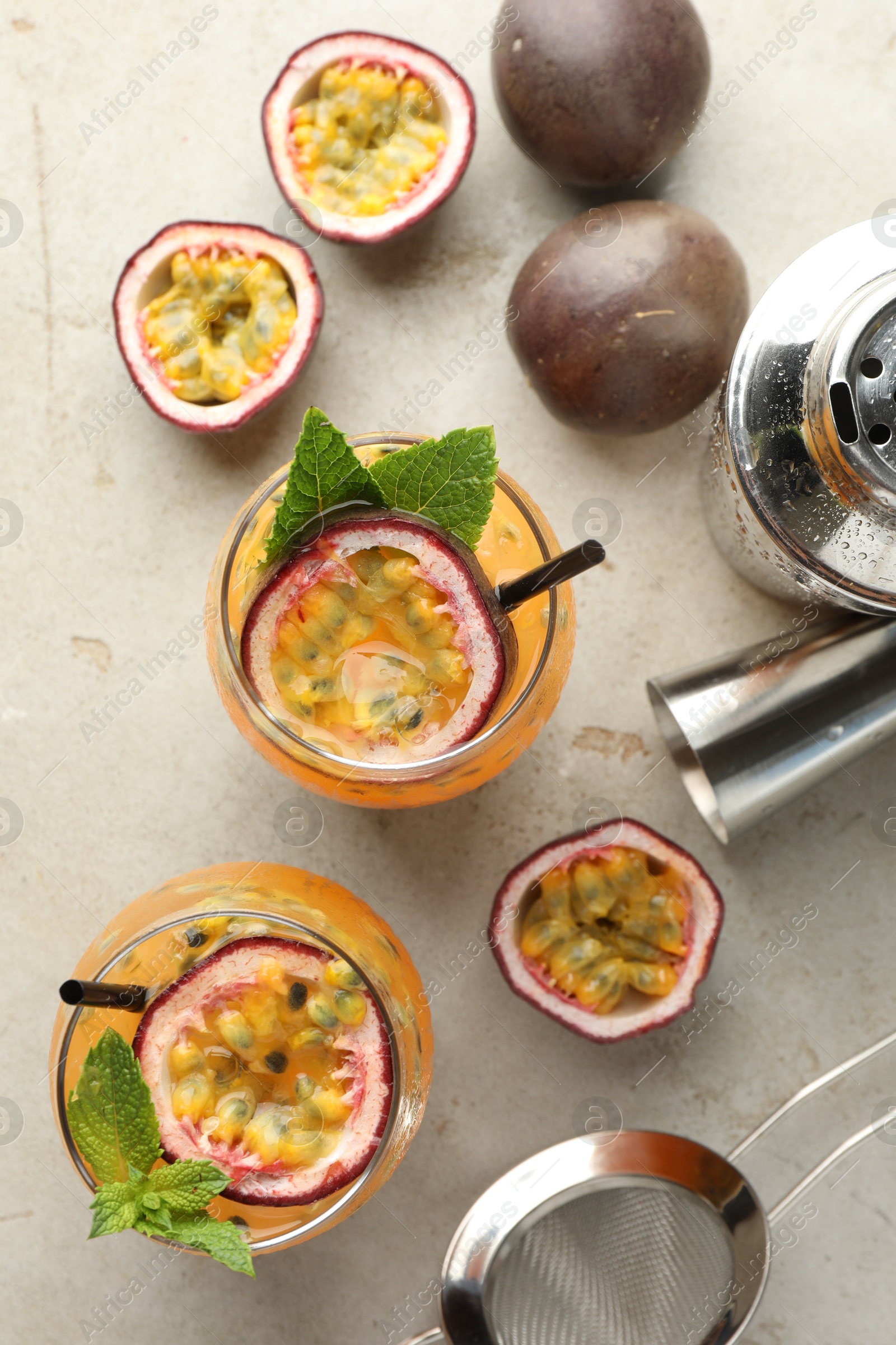 Tasty passion fruit drink with mint in glasses, fresh fruits and bartender's tools on gray textured table, flat lay Photo of Tasty passion fruit drink with mint in glasses, fresh fruits and bartender's tools on gray textured table, flat lay