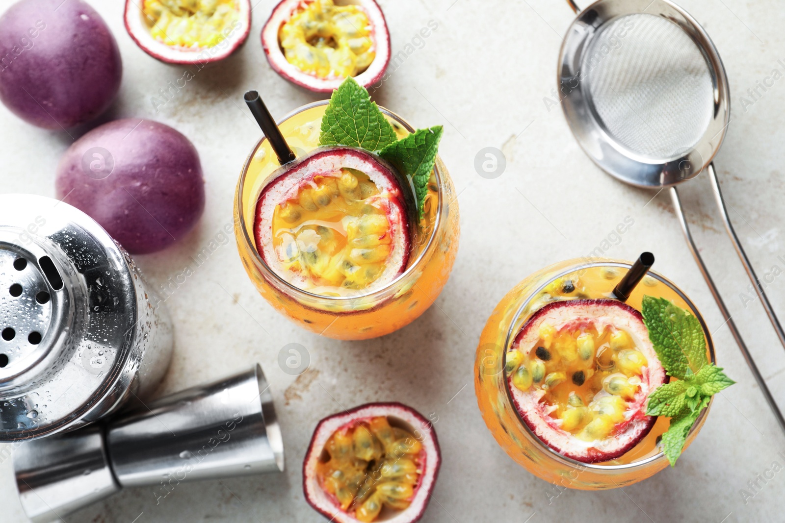 Tasty passion fruit drink with mint in glasses, fresh fruits and bartender's tools on gray textured table, flat lay Photo of Tasty passion fruit drink with mint in glasses, fresh fruits and bartender's tools on gray textured table, flat lay