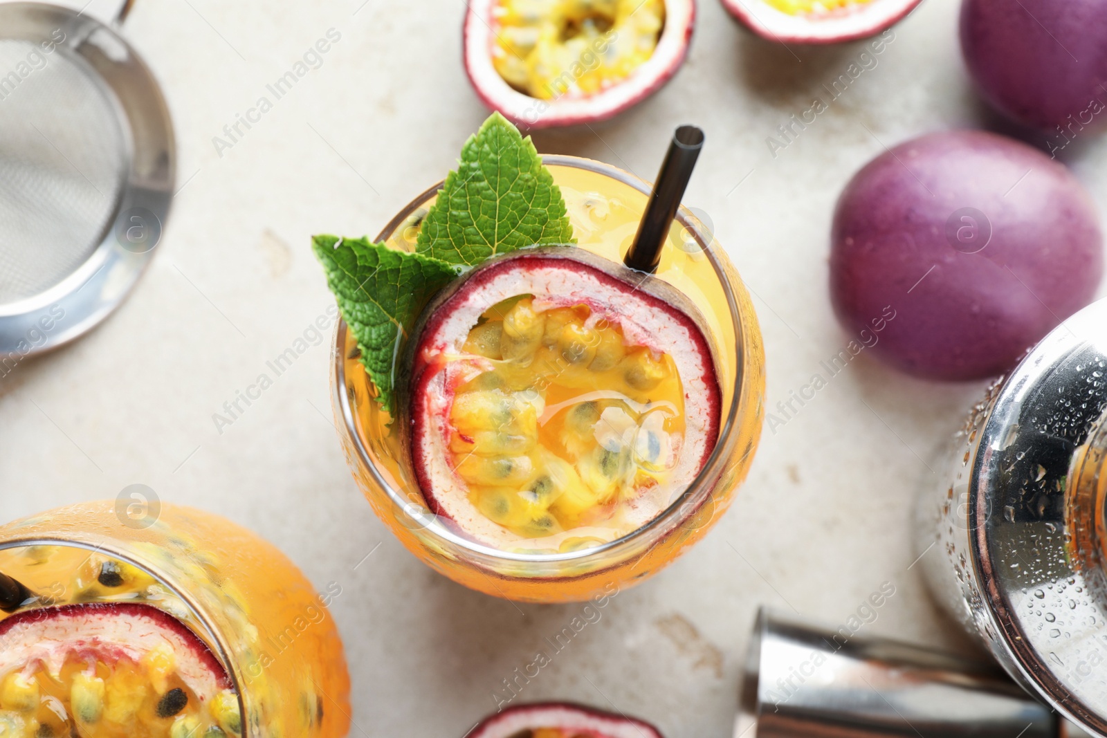 Tasty passion fruit drink with mint in glasses, fresh fruits and bartender's tools on gray table, flat lay Photo of Tasty passion fruit drink with mint in glasses, fresh fruits and bartender's tools on gray table, flat lay