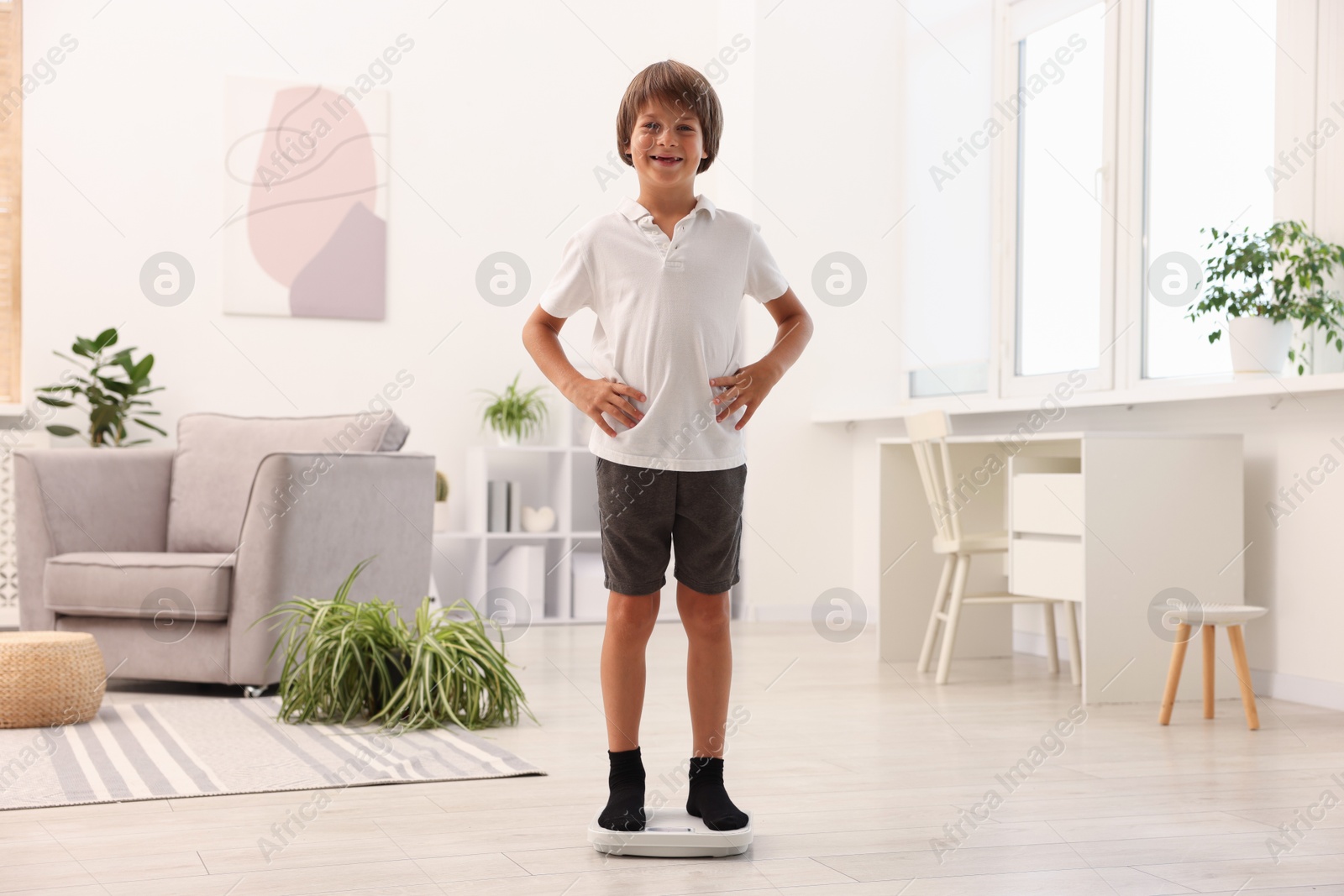 Photo of Little boy standing on scales at home