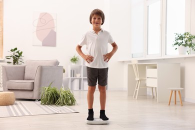 Photo of Little boy standing on scales at home