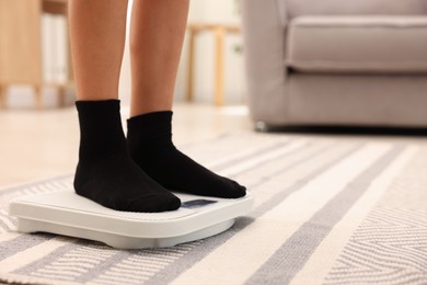 Photo of Little boy standing on scales indoors, closeup. Space for text