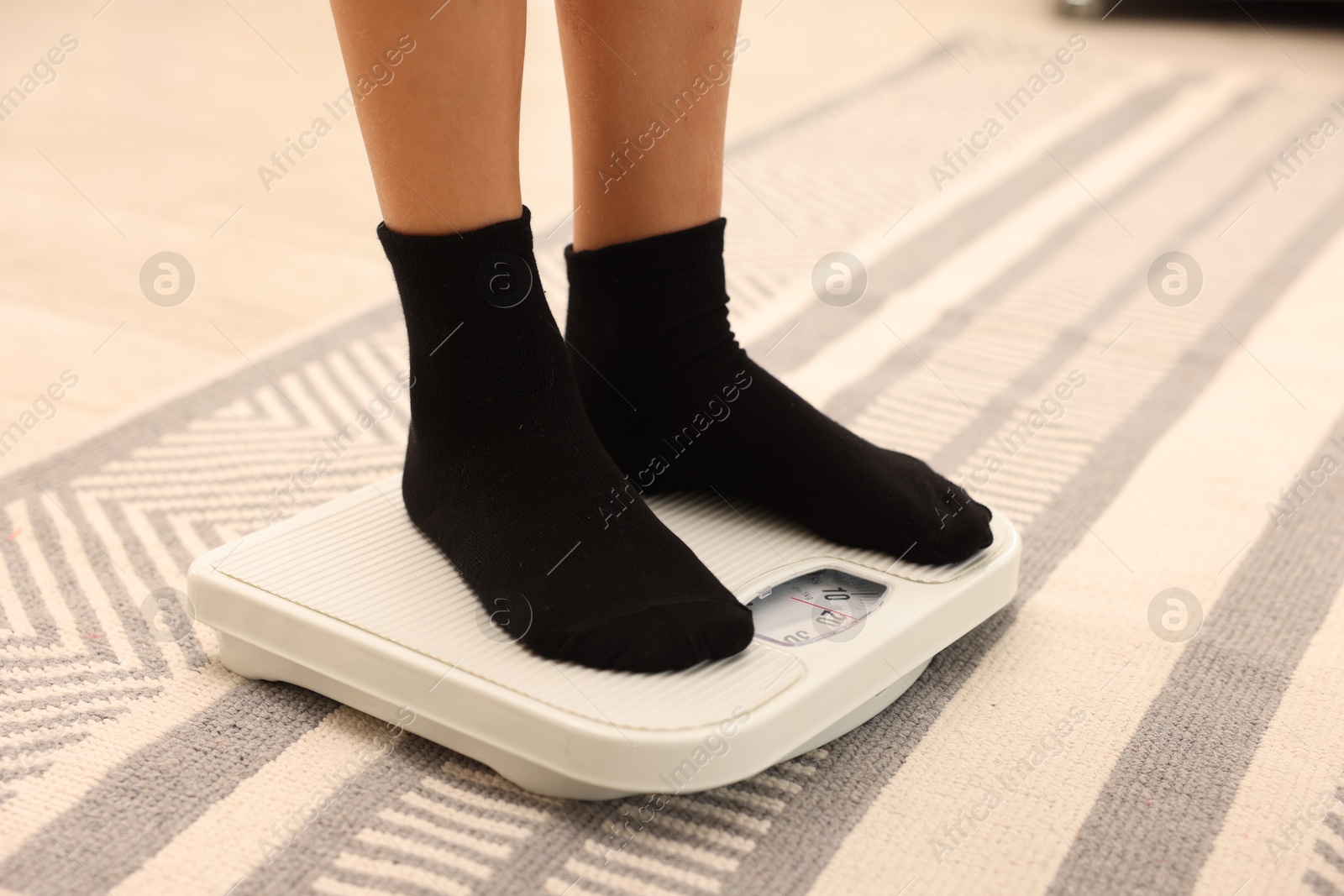 Photo of Little boy standing on scales indoors, closeup