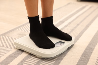 Photo of Little boy standing on scales indoors, closeup
