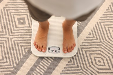 Photo of Little boy standing on scales indoors, top view