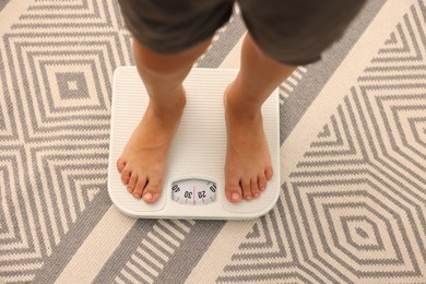 Photo of Little boy standing on scales indoors, top view