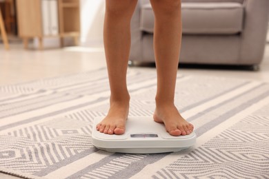 Photo of Little boy standing on scales indoors, closeup