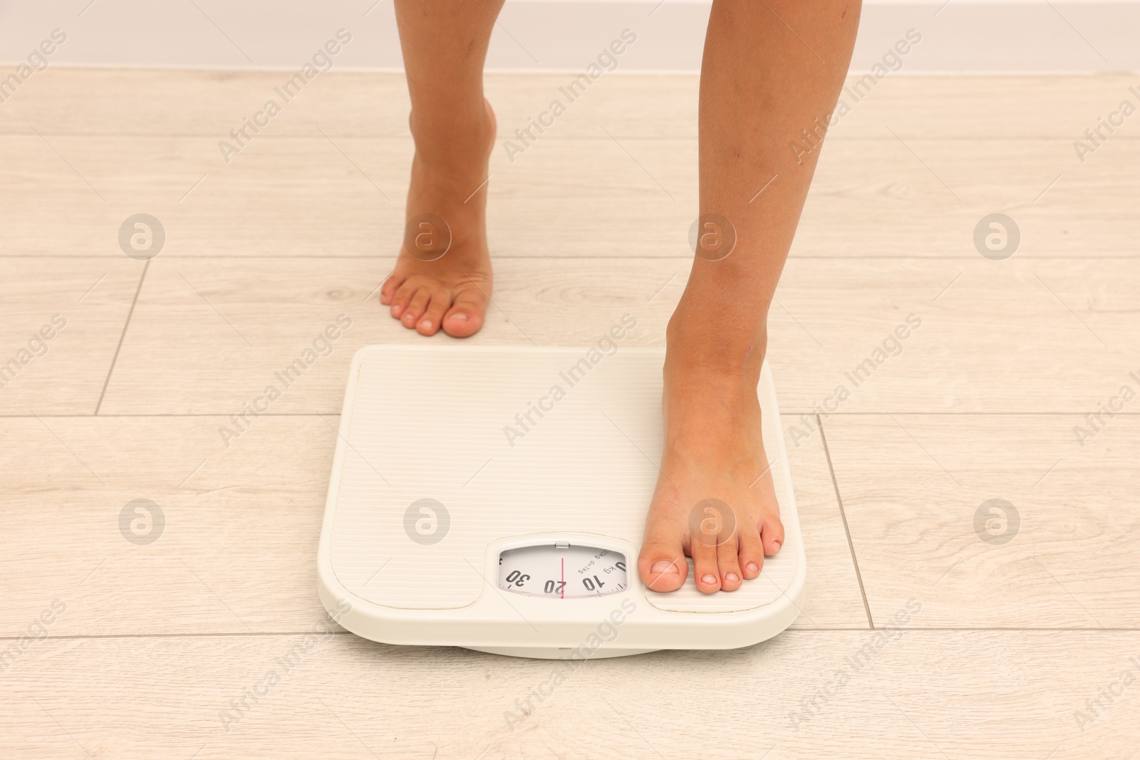 Photo of Little boy standing on scales indoors, closeup