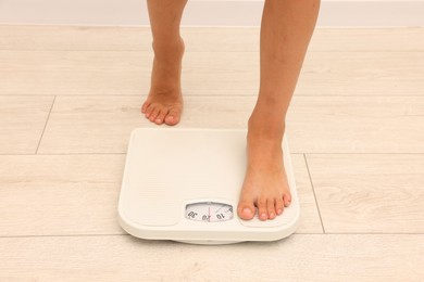 Photo of Little boy standing on scales indoors, closeup