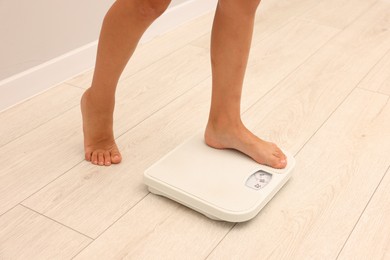 Photo of Little boy standing on scales indoors, closeup