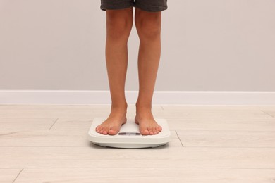Photo of Little boy standing on scales indoors, closeup