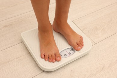 Photo of Little boy standing on scales indoors, closeup