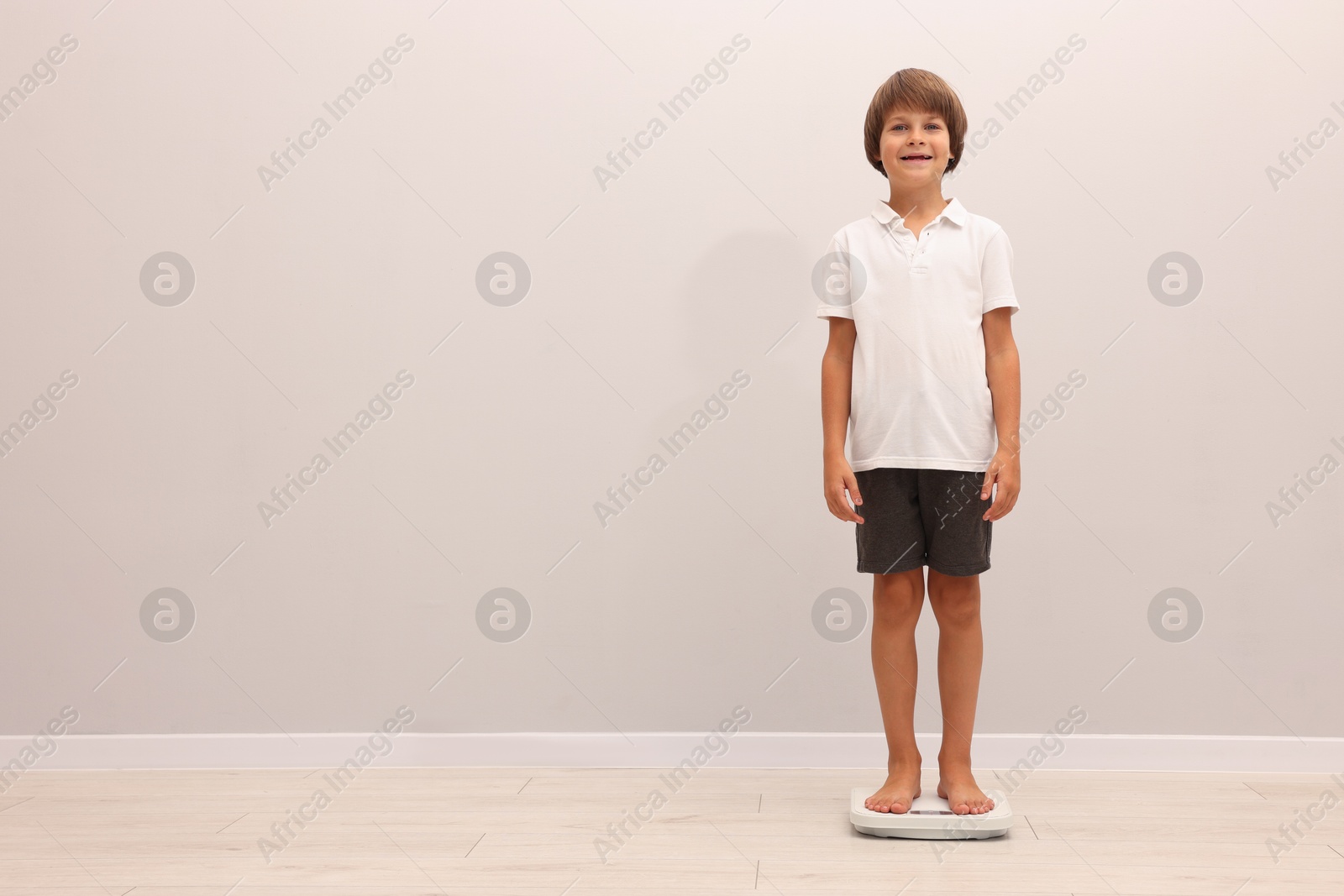 Photo of Little boy standing on scales indoors, space for text
