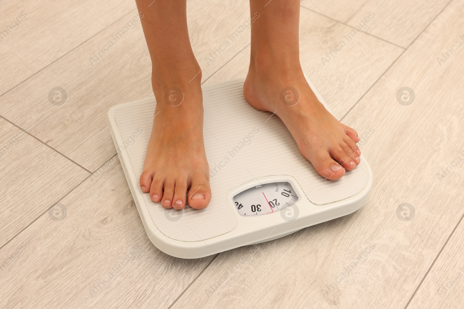 Photo of Little boy standing on scales indoors, closeup