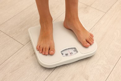 Photo of Little boy standing on scales indoors, closeup