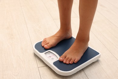Photo of Little boy standing on scales indoors, closeup. Space for text