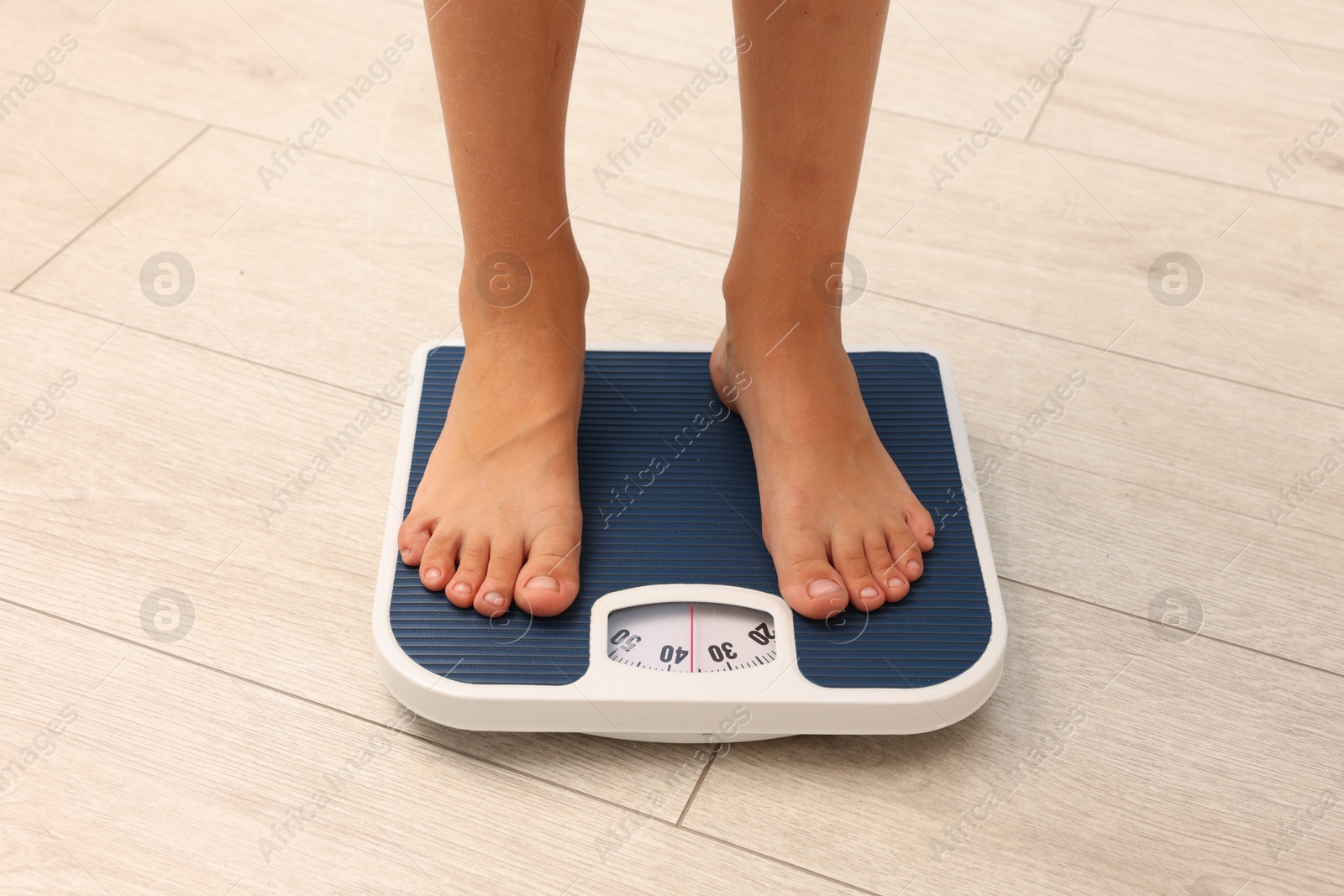 Photo of Little boy standing on scales indoors, closeup