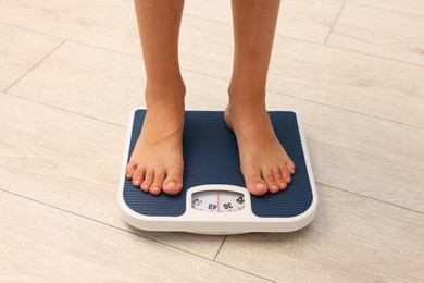 Photo of Little boy standing on scales indoors, closeup